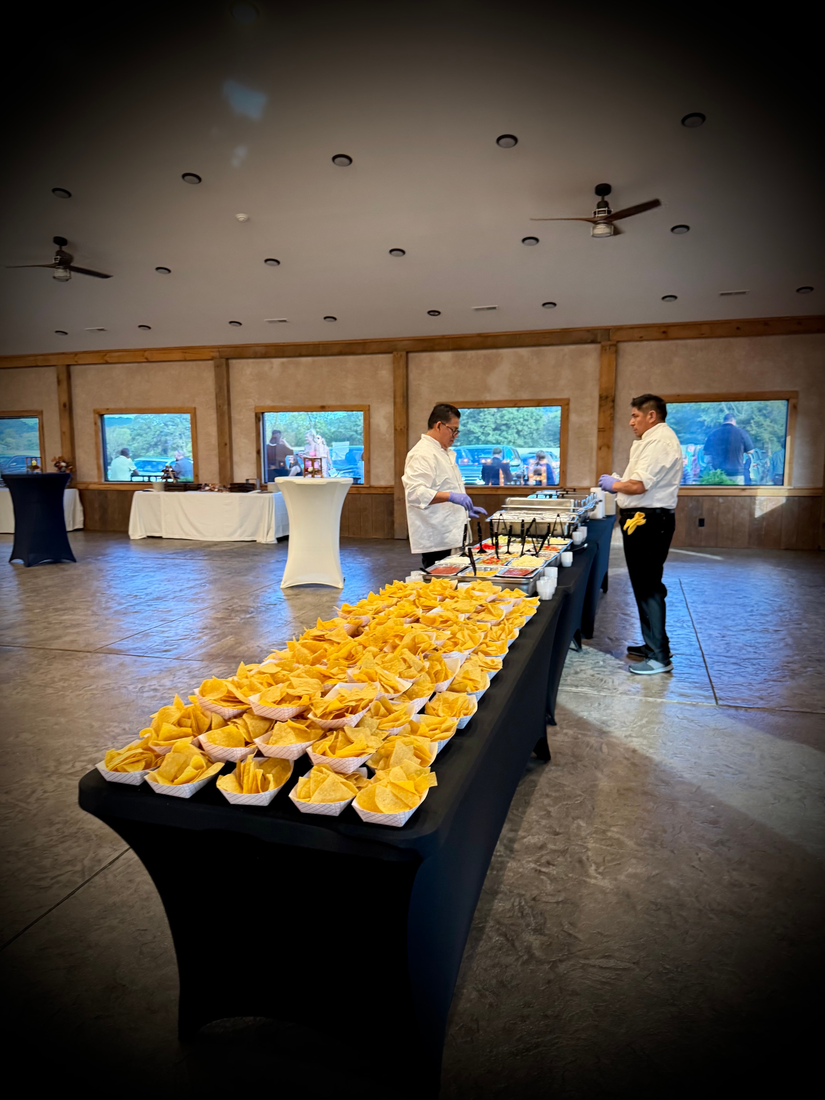 Long table of individual chip baskets with Salsas catering staff preparing the serving line