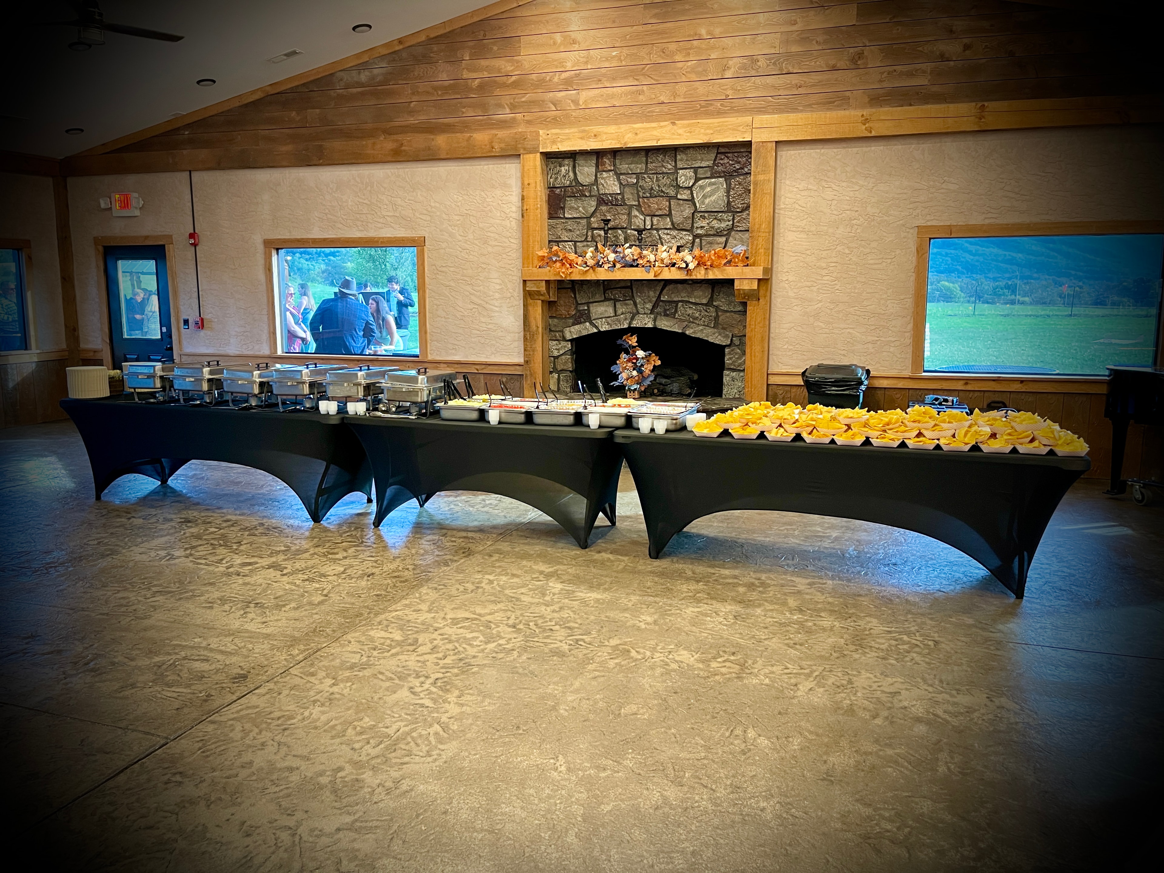 Salsas catering full buffet setup with chafing dishes and chip baskets in front of a stone fireplace