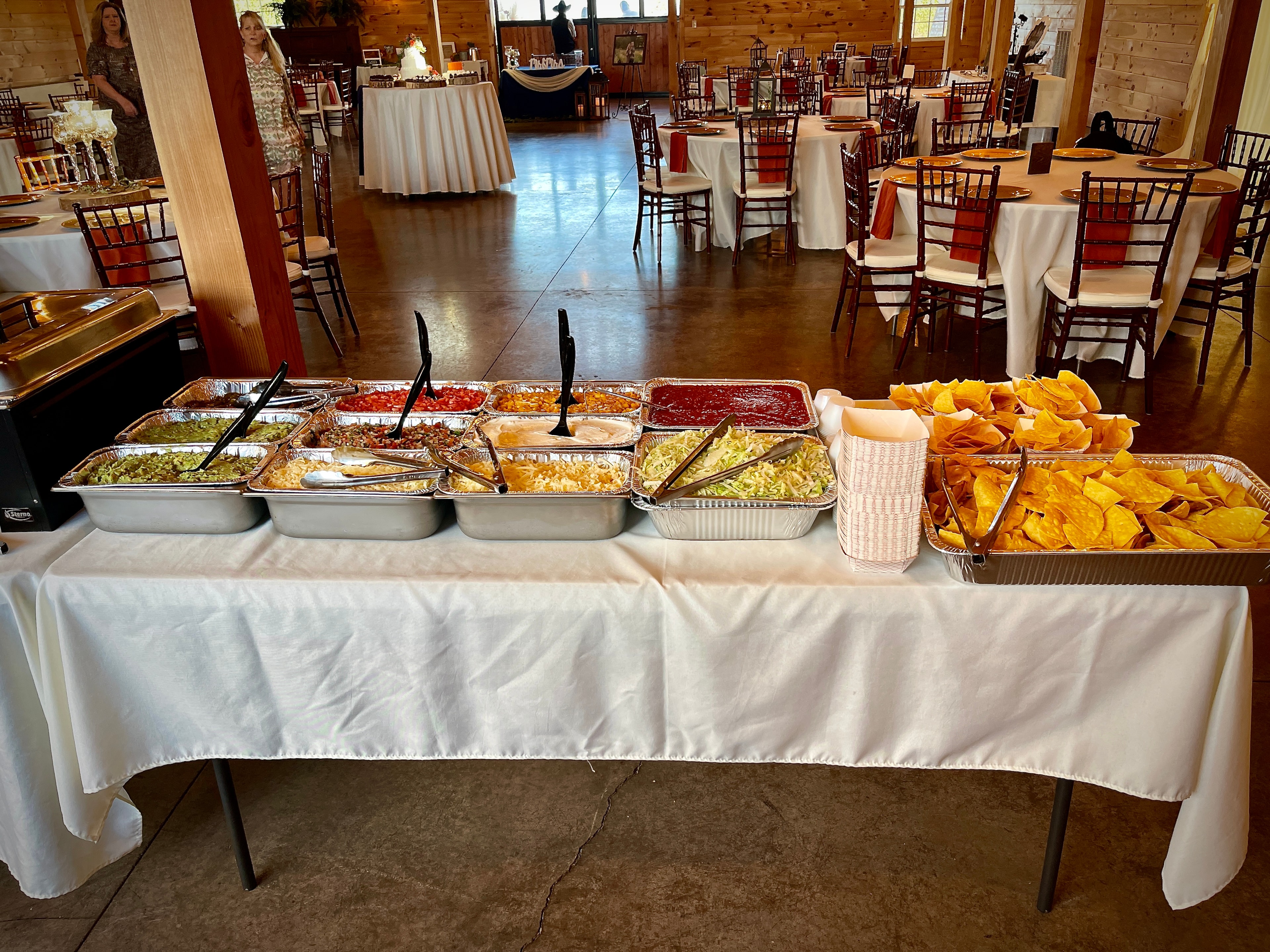 Full taco bar with guacamole, salsa, shredded cheese, pico de gallo and chips at a wedding reception