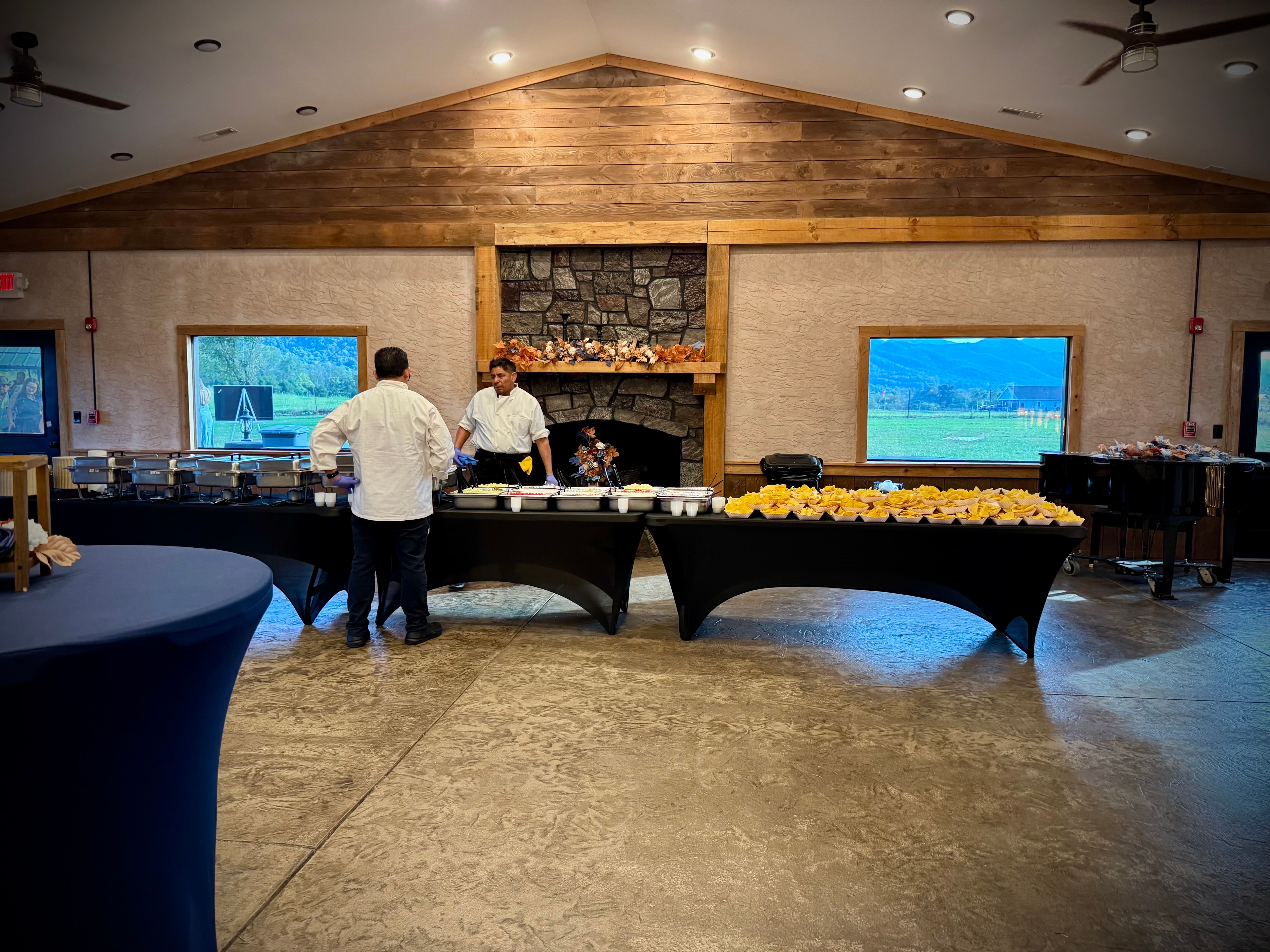 Salsas catering team in chef whites setting up chafing dishes and chip baskets at a fireplace venue